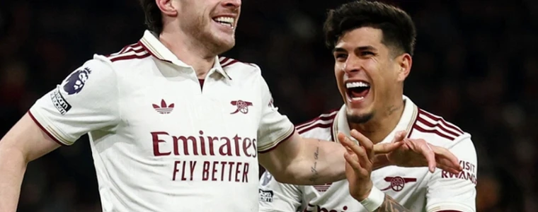 Áo đấu đỏ-trắng Arsenal và áo xanh Manchester City đặt cạnh cúp bạc trên sân cỏ có mái che, gợi trận Siêu cúp Anh tại Cardiff